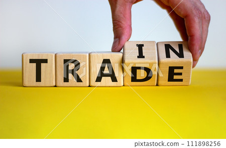 Hand flips cubes and changes the word 'train' to 'trade'. Beautiful wooden table, white background, copy space. Business concept. 111898256