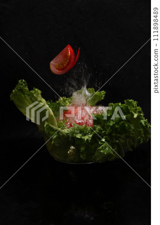 Vegetable salad and water splashes on black background Vegetable salad and water splashes on black background 111898489