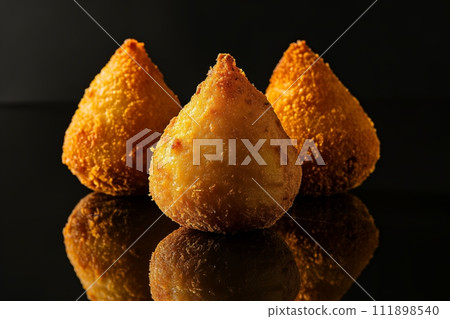 Coxinha, traditional Brazilian snack, stuffed with chicken and fried on black background 111898540