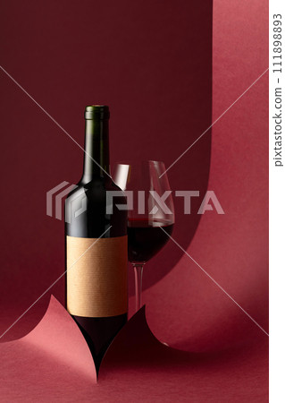 Bottle and glass of red wine on a red background. 111898893