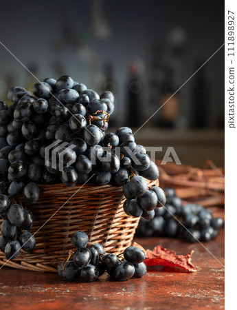 Blue grapes in old basket on a brown vintage table. Blue grapes in old basket on a brown vintage table. 111898927