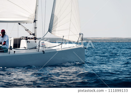 Side view of a sailing yacht during regatta in open sea Side view of a sailing yacht during regatta in open sea 111899133