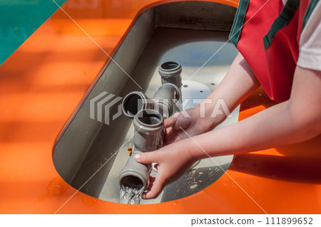 Child playing with water pipes and exploring what is plumbing in the kids museum Child playing with water pipes and exploring what is plumbing in the kids museum 111899652