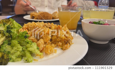 Broccoli with a dish of pilaf on the table while dining with friends. 111901329