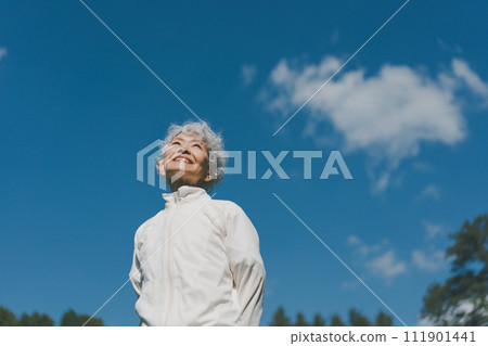 A woman in her 60s in the park looks at the sky A woman in her 60s in the park looks at the sky 111901441