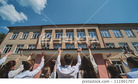 Berezovka, Belarus - May 31, 2023: Graduates say goodbye to the school and wave goodbye. 111901707