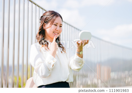 一位女性/女商人一邊照鏡子一邊摸嘴（牙齒、牙齒排列、潔白牙齒、美白、口紅、嘴唇、嘴唇） 111901983
