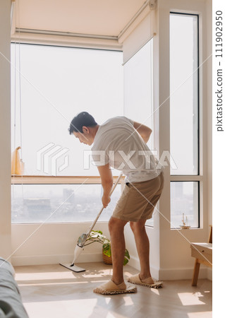 Asian Thai man using mop for cleaning floor in living room apartment, Man do household chores, housework concept. Asian Thai man using mop for cleaning floor in living room apartment, Man do household chores, housework concept. 111902950