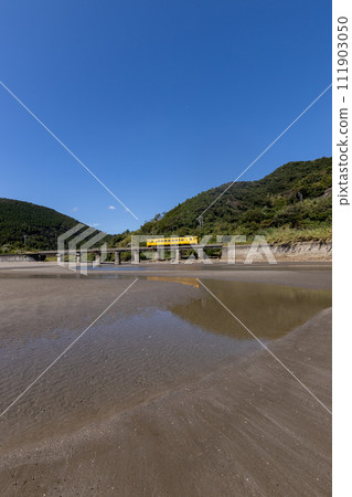 Sand pattern and blue sky at low tide, JR Kyushu Nichinan Line yellow DL Kiha 40 reflected on the tide stop 111903050