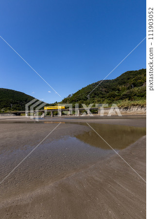 Sand pattern and blue sky at low tide, JR Kyushu Nichinan Line yellow DL Kiha 40 reflected on the tide stop 111903052