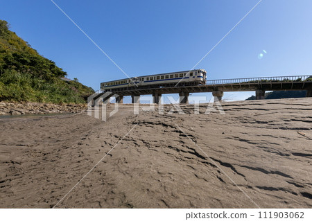 JR Kyushu Nichinan Line white DL Kiha 40 running on the Shimotetsu Bridge with sand pattern and blue sky JR Kyushu Nichinan Line white DL Kiha 40 running on the Shimotetsu Bridge with sand pattern and blue sky 111903062