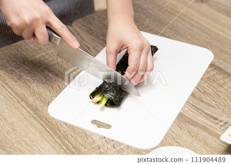 Woman's hands cutting sushi rolls 111904489