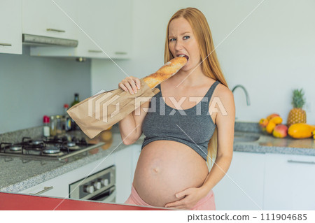 Pregnant woman eating bread in the kitchen. Exploring the impact of gluten during pregnancy: understanding the potential benefits and risks for maternal health and fetal development Pregnant woman eating bread in the kitchen. Exploring the impact of gluten during pregnancy: understanding the potential benefits and risks for maternal health and fetal development 111904685