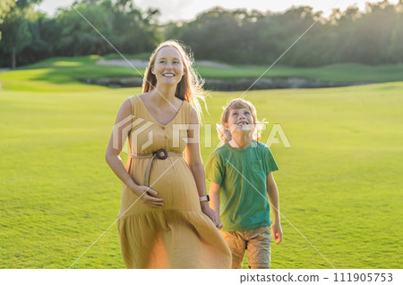 Heartwarming outdoor bonding as a pregnant mom and her son enjoy quality time together, savoring the beauty of nature and creating cherished moments 111905753