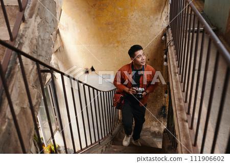 Excited photographer looking around when walking up stairs in abandoned decaying building 111906602