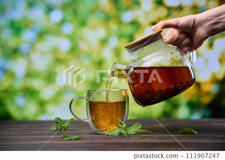 natural organic herbal tea pours in a glass from glass teapot 111907247