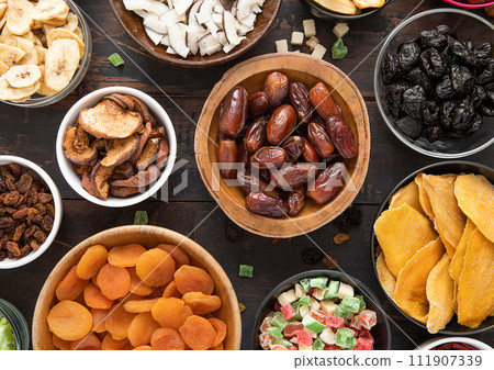 Mixed healthy dried sweet berries and fruits snack in various bowl plates on wooden background. 111907339