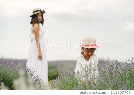 Mother with little daughter on lavender background. Beautiful woman and cute baby playing in meadow field. Family holiday in summer day. Mother with little daughter on lavender background. Beautiful woman and cute baby playing in meadow field. Family holiday in summer day. 111907701