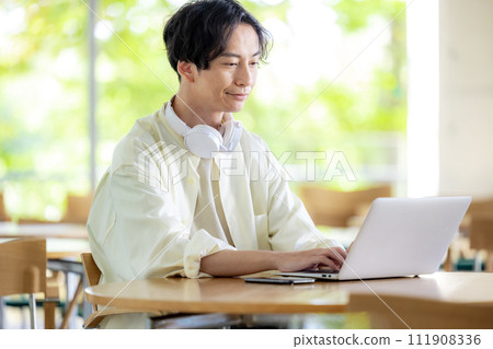 A man is working in a cafe with his computer open 111908336
