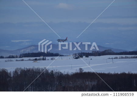 Jetstar plane flying over the hills of Biei in winter Jetstar plane flying over the hills of Biei in winter 111908559
