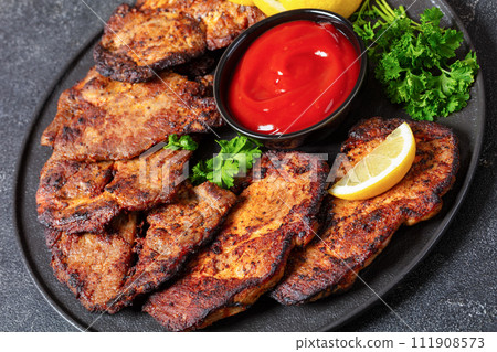 fried juicy pork steaks with ketchup on plate 111908573
