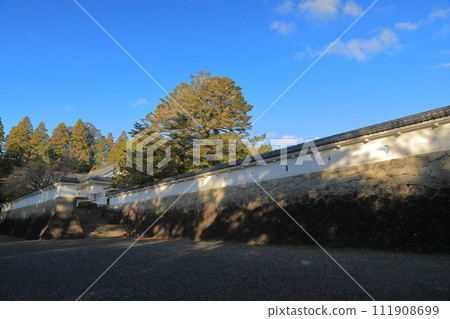 The long white walls of Obi Castle ruins in Nichinan City shine against the blue sky 111908699