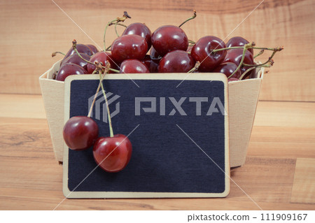 Fresh ripe juicy cherries in container. Dessert or snack. Copy space for text on black board Fresh ripe juicy cherries in container. Dessert or snack. Copy space for text on black board 111909167