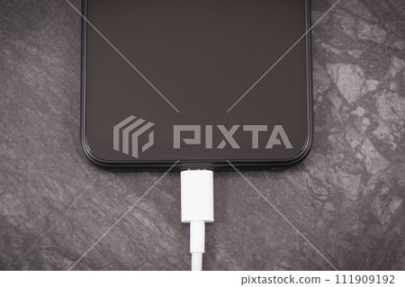 Smartphone with connected plug of charger. Telephone charging 111909192