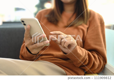 Young woman in casual clothes using mobile phone on couch at home Young woman in casual clothes using mobile phone on couch at home 111909812