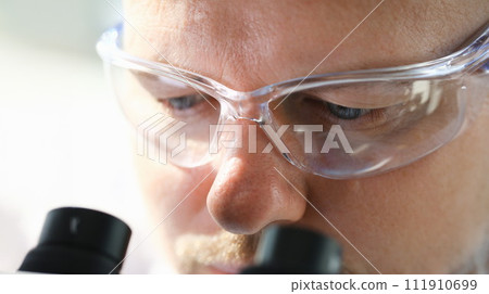 Male scientist looking through binocular 111910699