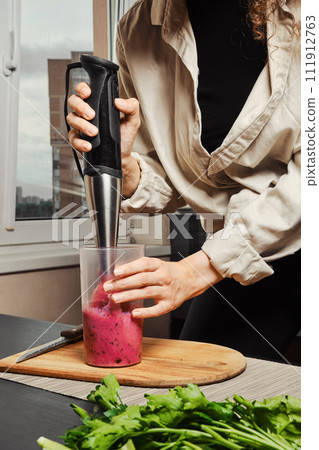 Unrecognizable woman making smoothie with banana and black currant 111912763