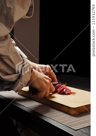 Closeup of hands of woman slicing raw beef meat on thin slices 111912769