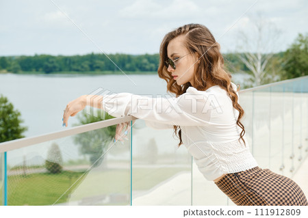 Young woman with long hair enjoying beautiful view from balcony 111912809