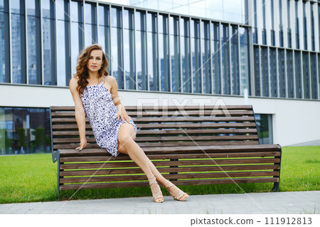 Beautiful woman with long legs sitting on bench 111912813