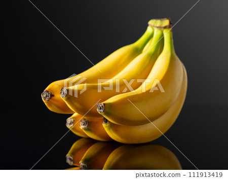 Bananas on a black reflective background. 111913419