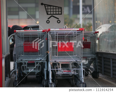 Trolleys near supermarket. Metal baskets on wheels are connected to each other. 111914254