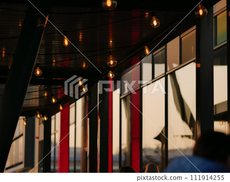 Glass showcases and reflection of the setting sun. Red glowing panels. People Glass showcases and reflection of the setting sun. Red glowing panels. People 111914255