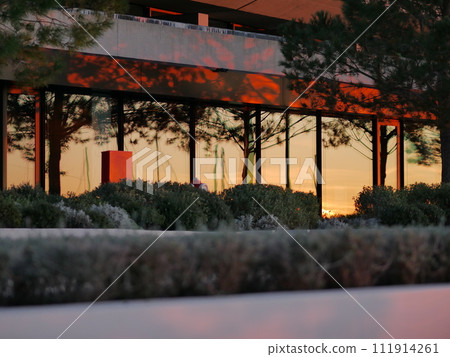 Facade of a building in the rays of the sun at sunset. Reflection of the sunset 111914261