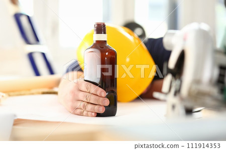 Arm of drunken worker in yellow helmet hold liquor 111914353