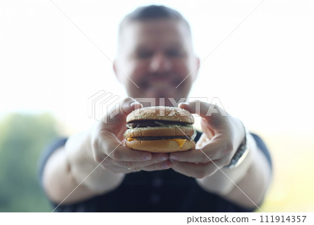 Satisfied young man holding a hamburger Satisfied young man holding a hamburger 111914357