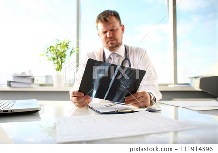 Male doctor hold in arm silver pen and look at xray Male doctor hold in arm silver pen and look at xray 111914396