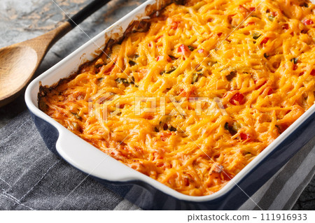 King Ranch Casserole is classic Texas comfort food with vegetables, cheddar cheese, tortilla and cream close-up in a baking dish. Horizontal 111916933