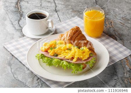 Scrambled egg sandwich with ham, green onions and lettuce served with orange juice and coffee close-up. Horizontal 111916946