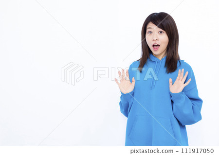 A woman wearing a blue hoodie smiling and looking surprised 111917050