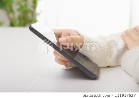 Hands of a woman looking at a smartphone 111917627