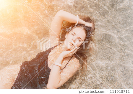 Woman summer travel sea. Happy tourist enjoy taking picture outdoors for memories. Woman traveler posing on the beach at sea surrounded by volcanic mountains, sharing travel adventure journey 111918711