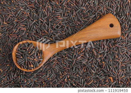 Black rice in a wooden spoon as a background. Top view. Flat lay Black rice in a wooden spoon as a background. Top view. Flat lay 111919450