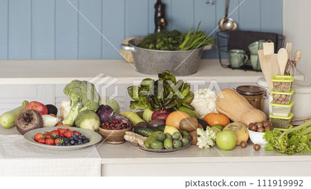 Fresh greenery, vegetables, berries and fruits on a white table in the kitchen at a country cottage, indoor, selective focus. 111919992