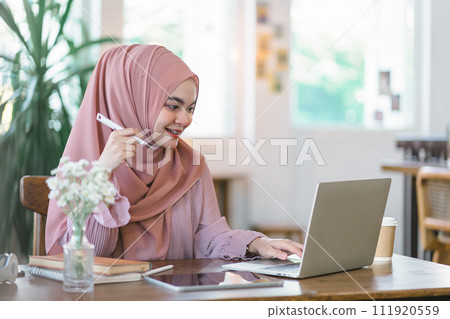Beautiful Arabic businesswoman in a hijab discussing financial planning data with laptop at creative workplace. 111920559