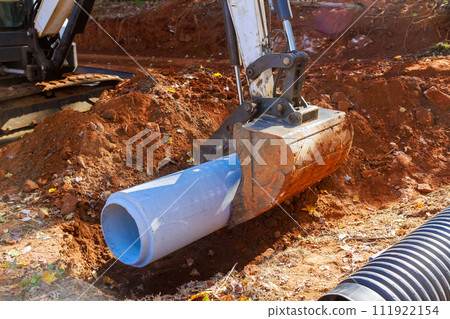 Laying pipes to feed rainwater into water main collector at construction site 111922154